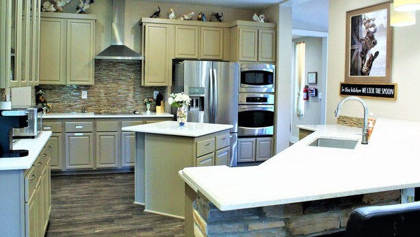 A modern kitchen with light wood cabinets, stainless steel appliances, a central island, and decorative wall art. - The Escape -family Friendly Close to Fiesta Texas (San Antonio)