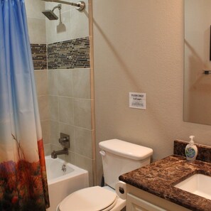 A bathroom with a shower, toilet, and sink.