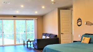A bedroom with a bed, a sofa, a small table, and a sliding glass door leading to a balcony. - The Escape -family Friendly Close to Fiesta Texas (San Antonio)