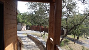 A wooden deck leading to a house with a view of a fenced yard and trees. - The Den - Family Friendly Close to Fiesta Texas (San Antonio)