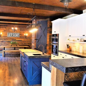 A modern kitchen with a wooden island, built-in appliances, and a 'LET'S EAT' sign on the wall. - The Rustic Inn- Family Friendly Near Fiesta Texas (San Antonio)