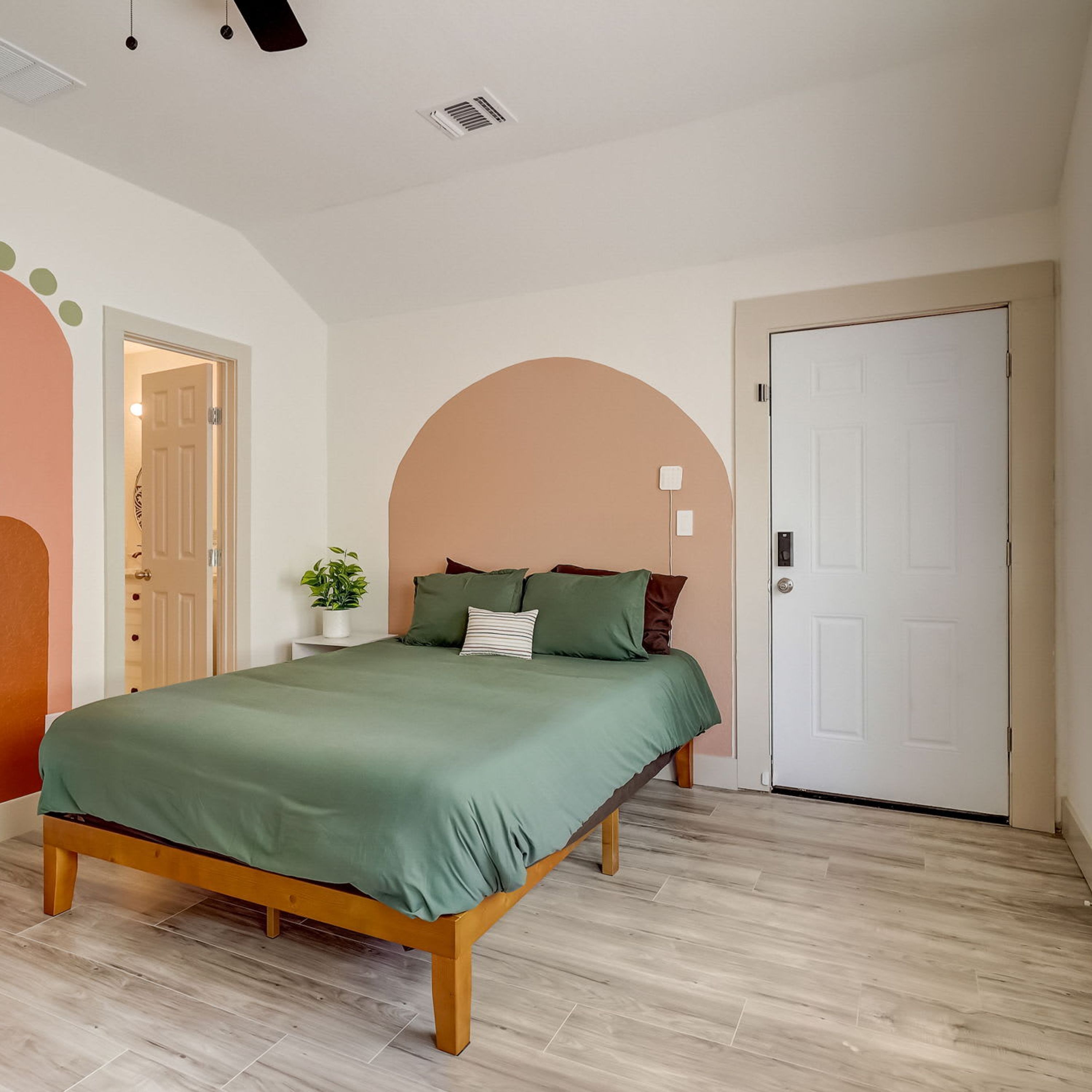 A bedroom with a bed, a potted plant, and a door.