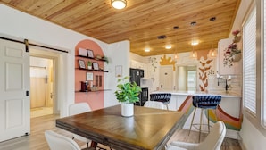 Una cocina moderna con techo de madera, paredes blancas y una isla central con taburetes de bar.
