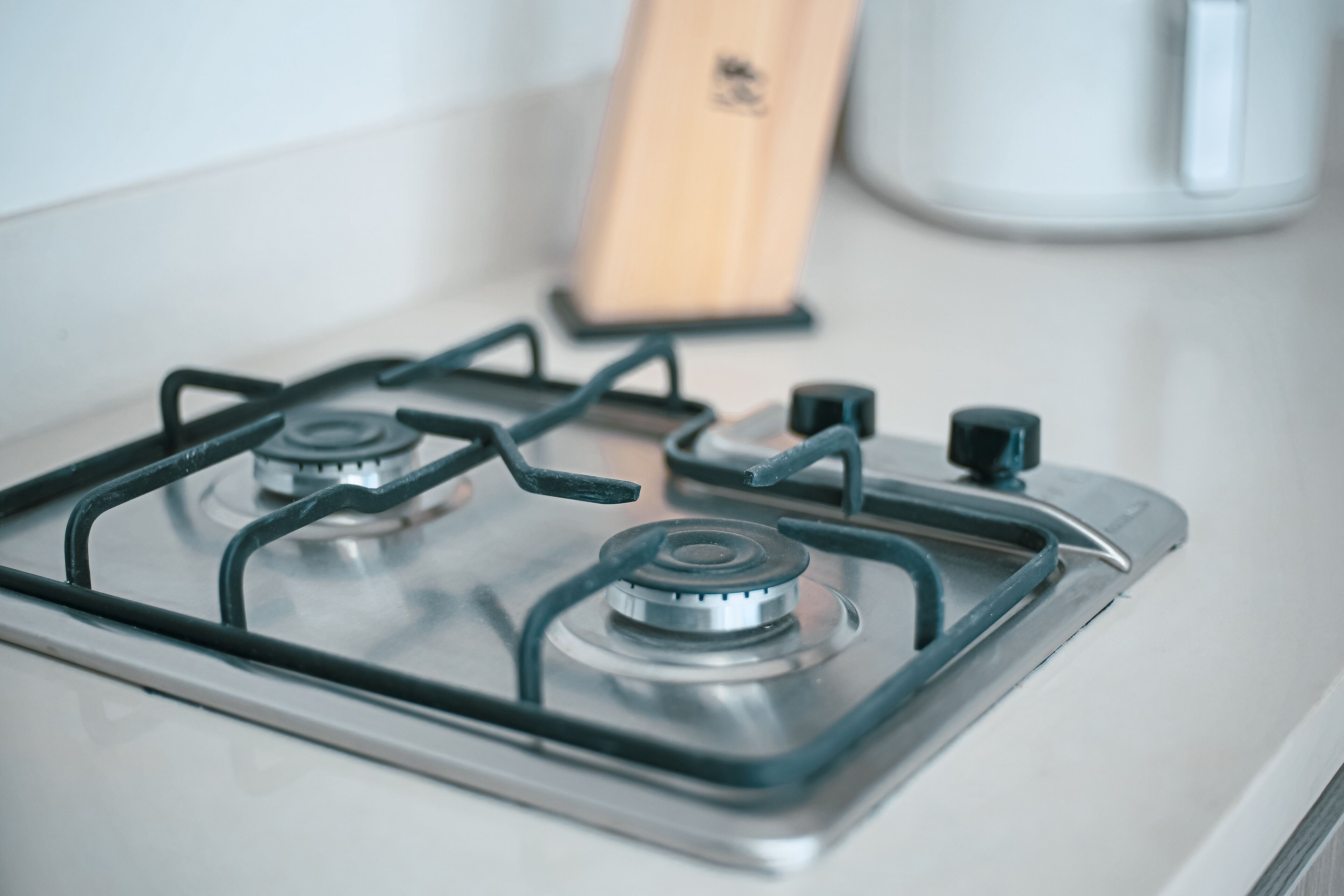 A kitchen with a gas stove, a coffee maker, and a wooden cutting board.
