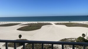 A beach with a clear sky, sandy areas, and some vegetation. - Paradise on the Beach (Treasure Island)