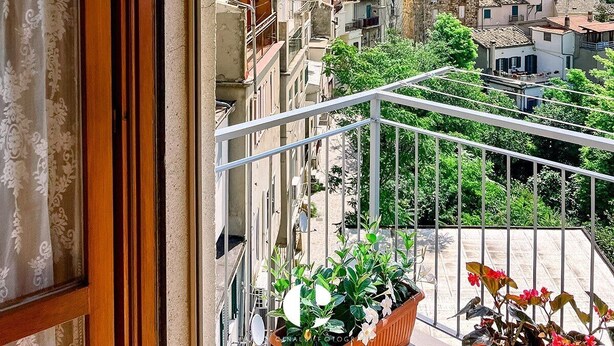 Un balcon offrant une vue sur le paysage urbain, avec notamment une tour et divers bâtiments.