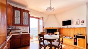 Une cuisine avec des meubles en bois, une table à manger avec des chaises, un téléviseur et une cheminée.