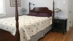 A bedroom with a four-poster bed, two bedside tables, a nightstand, a framed picture on the wall, and a door. - WINTER RENTAL - Single Family House Sleeps 8 (Ocean City)