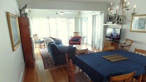 A spacious living room with a blue sofa, a dining table with chairs, and a chandelier. - WINTER RENTAL - Single Family House Sleeps 8 (Ocean City)