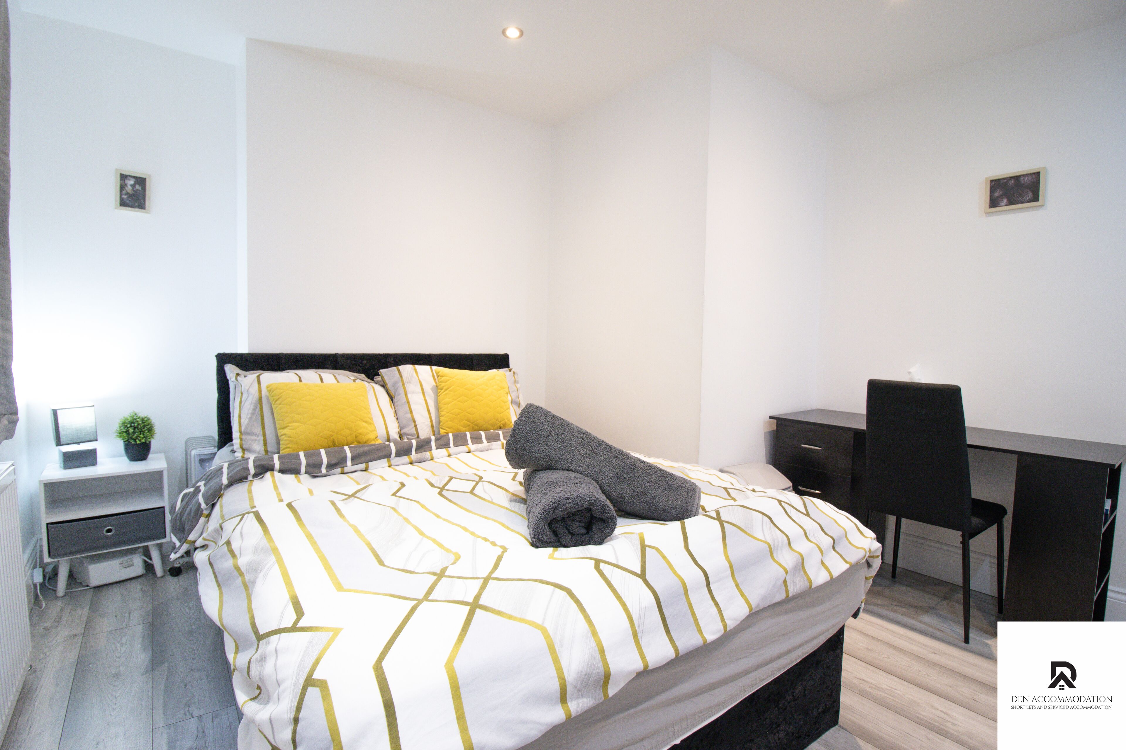 A modern bedroom with a bed, bedside table, and a desk.