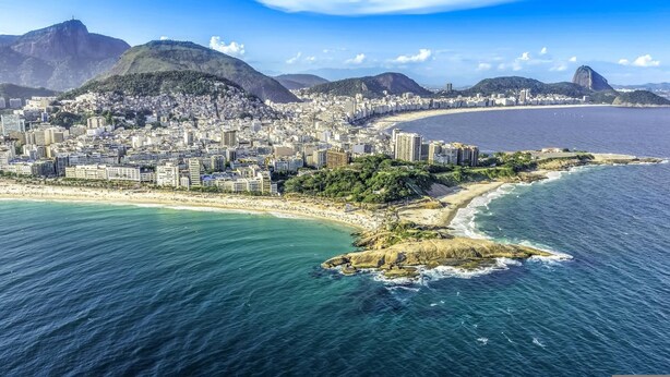 Un paysage urbain côtier caractérisé par une montagne imposante, une plage et une zone urbaine densément construite.