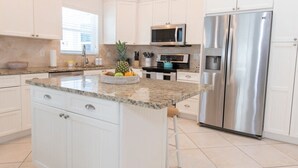 A modern kitchen with white cabinetry, a stainless steel refrigerator, a microwave, and a granite countertop. - Clean Spacious Waterfront 2bd 2ba Sleeps 8 (Fort Pierce)