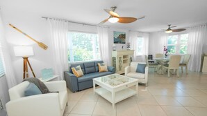 Amplia sala de estar con sofá, sillones, una mesa de centro y un comedor con sillas y una mesa.