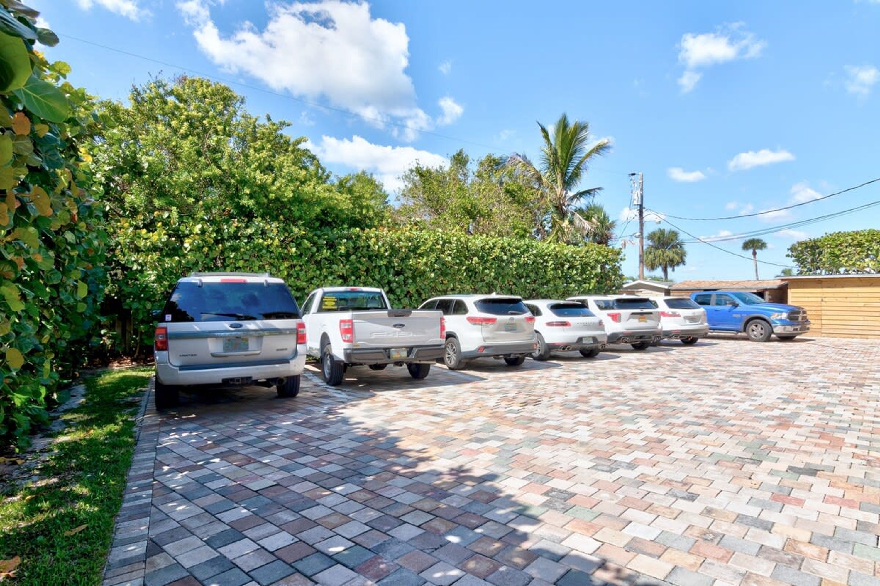 A parking lot with several vehicles, including SUVs and a pickup truck, parked on a paved surface.
