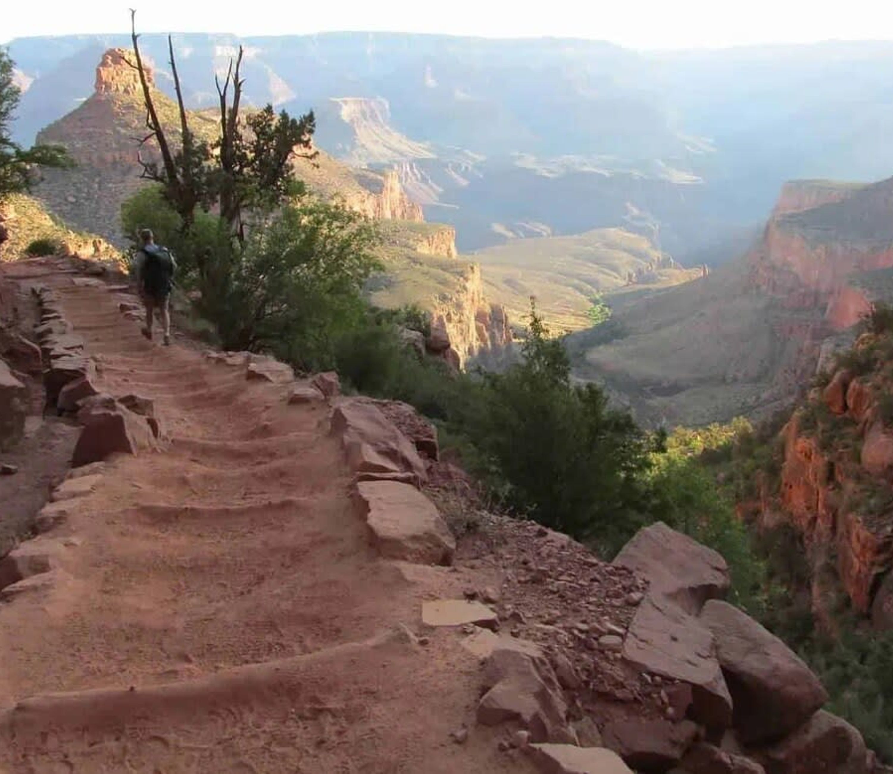 Sendero para excursionismo con escalones rocosos y vista a un cañón.