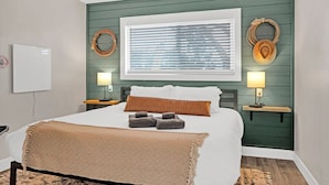 A bedroom with a bed, two bedside tables, a ceiling fan, a window with blinds, and wall-mounted decor.