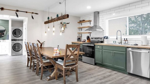 A modern kitchen with a dining area, built-in appliances, and a large window.