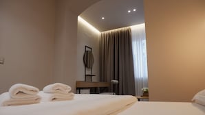 A hotel room with a neatly made bed, a bedside table with a lamp, a mirror, and a window with curtains. - D rooms City-center Tirana (Tirana)