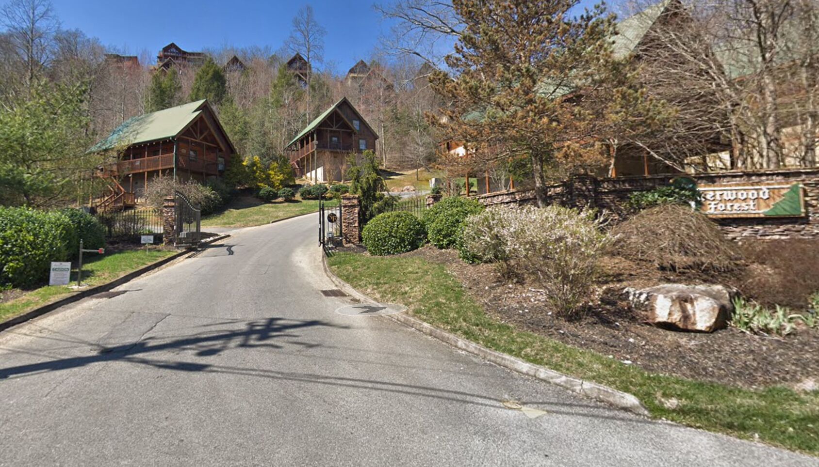 Un camino que lleva a una hilera de cabañas de madera, con un letrero que dice "Forest Inn".