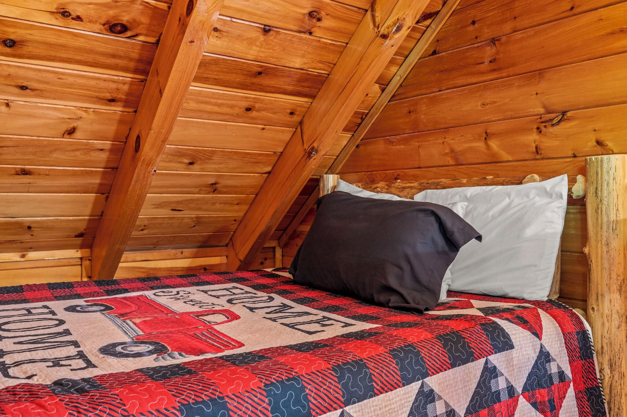 A cozy attic bedroom with wooden walls and a sloped ceiling.