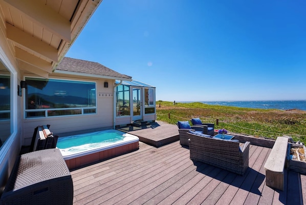 A deck with a hot tub, outdoor seating, and a view of the ocean. - Lands End - Ocean Front w/Beach Path & Spa (Gold Beach)