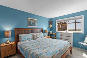 A bedroom with a bed, bedside tables, a dresser, a window with a view, and a painting on the wall. - Lands End - Ocean Front w/Beach Path & Spa (Gold Beach)