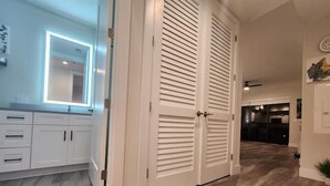 A hallway with a wooden floor, white cabinets, and a double door with louvered panels. - Lux place  green Cozy 3 Beds 2rooms (West Palm Beach)