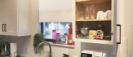 A modern kitchen with white cabinets, a built-in window, and a coffee maker.