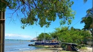 Una playa con un barco fondeado cerca de la orilla, rodeada de vegetación y cielos despejados.