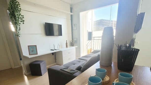 Una sala de estar moderna con una mesa de comedor de madera, un sofá y un televisor montado en la pared.