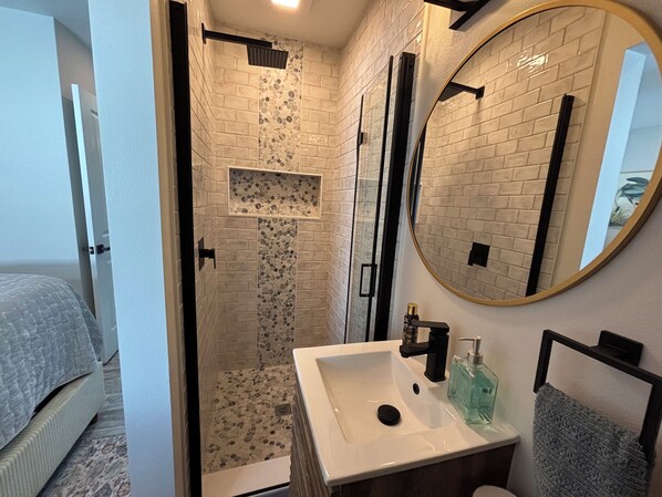 Un baño moderno con ducha, lavamanos y espejo.