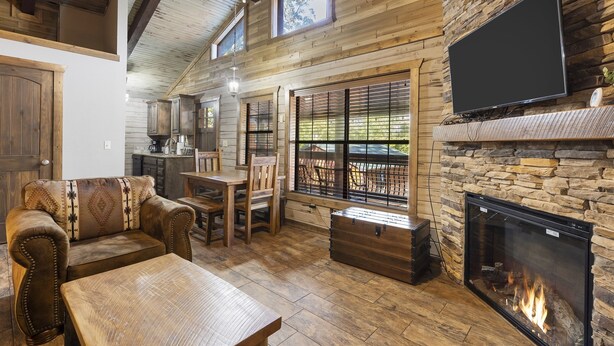 A cozy living room with a fireplace, wooden furniture, and a television mounted on the wall. - Peaceful Family Lake House near SDC Walk to Lake (Branson)