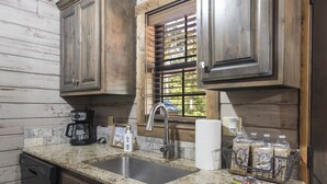 A kitchen with wooden cabinets, a granite countertop, a stainless steel sink, a coffee maker, and a window with blinds. - Peaceful Family Lake House near SDC Walk to Lake (Branson)