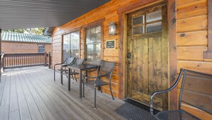 A wooden cabin with a porch, a table, and two chairs. - Peaceful Family Lake House near SDC Walk to Lake (Branson)