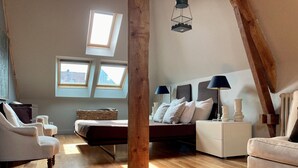 A bedroom with a loft-style ceiling, a bed with white linens, two bedside tables with lamps, a wicker chair, and a wooden floor. - Maison de Bord de Mer, Calme, Avec Joli Jardin Clos de Murs, 4min de la Plage ! (Concarneau)