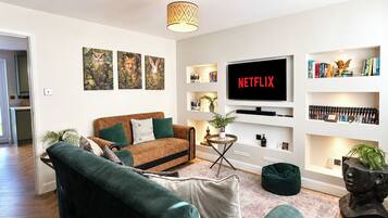Una sala de estar con sofá, mesa de centro, televisor y estanterías.
