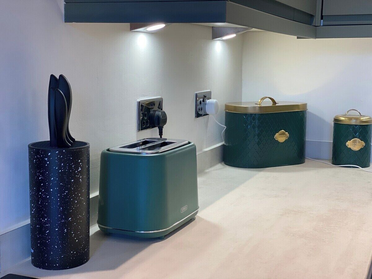 A kitchenette with a toaster, a kettle, and two storage containers.