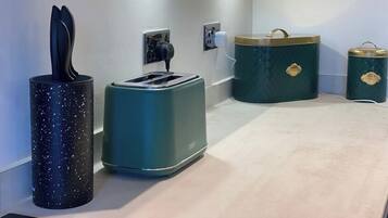 A kitchenette with a toaster, a kettle, and two storage containers.