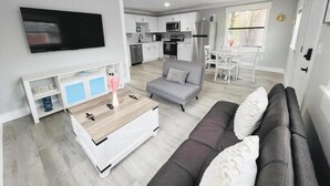 Ein modernes Wohnzimmer mit einem grauen Sofa, einer weißen Unterhaltungseinheit und einem an der Wand montierten Fernseher.