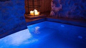 A stone-walled pool with a candle in a metal cage, under a blue-lit arch. - SUITE LE GROTTE - suite with heated pool and whirlpool (Ostuni)