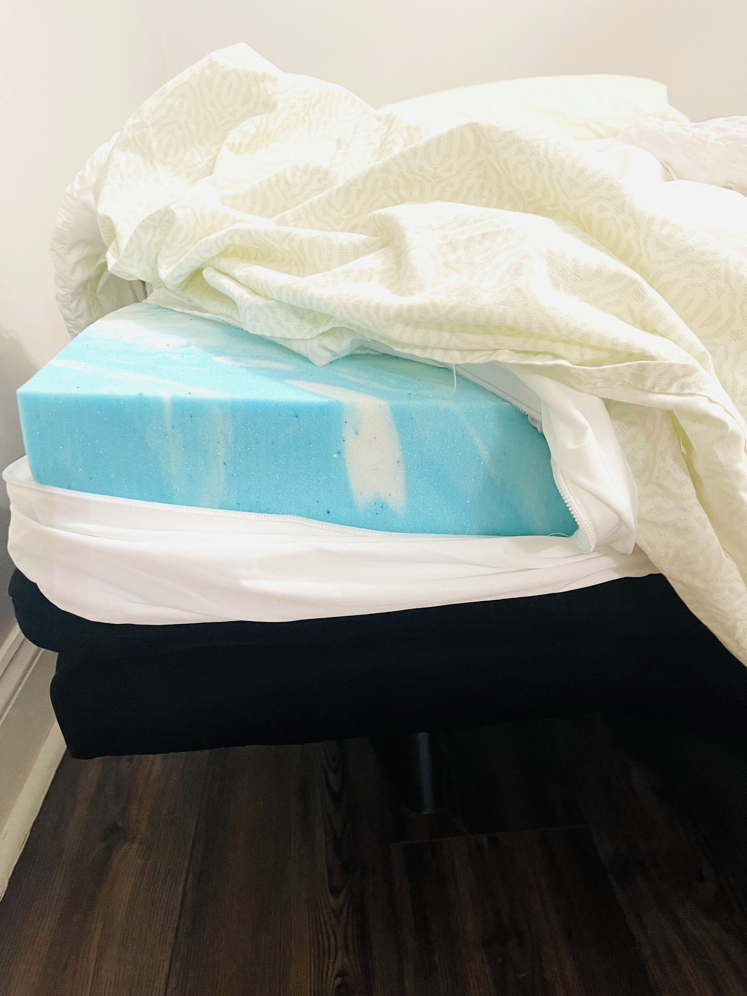 A bed with a white blanket and a blue mattress.