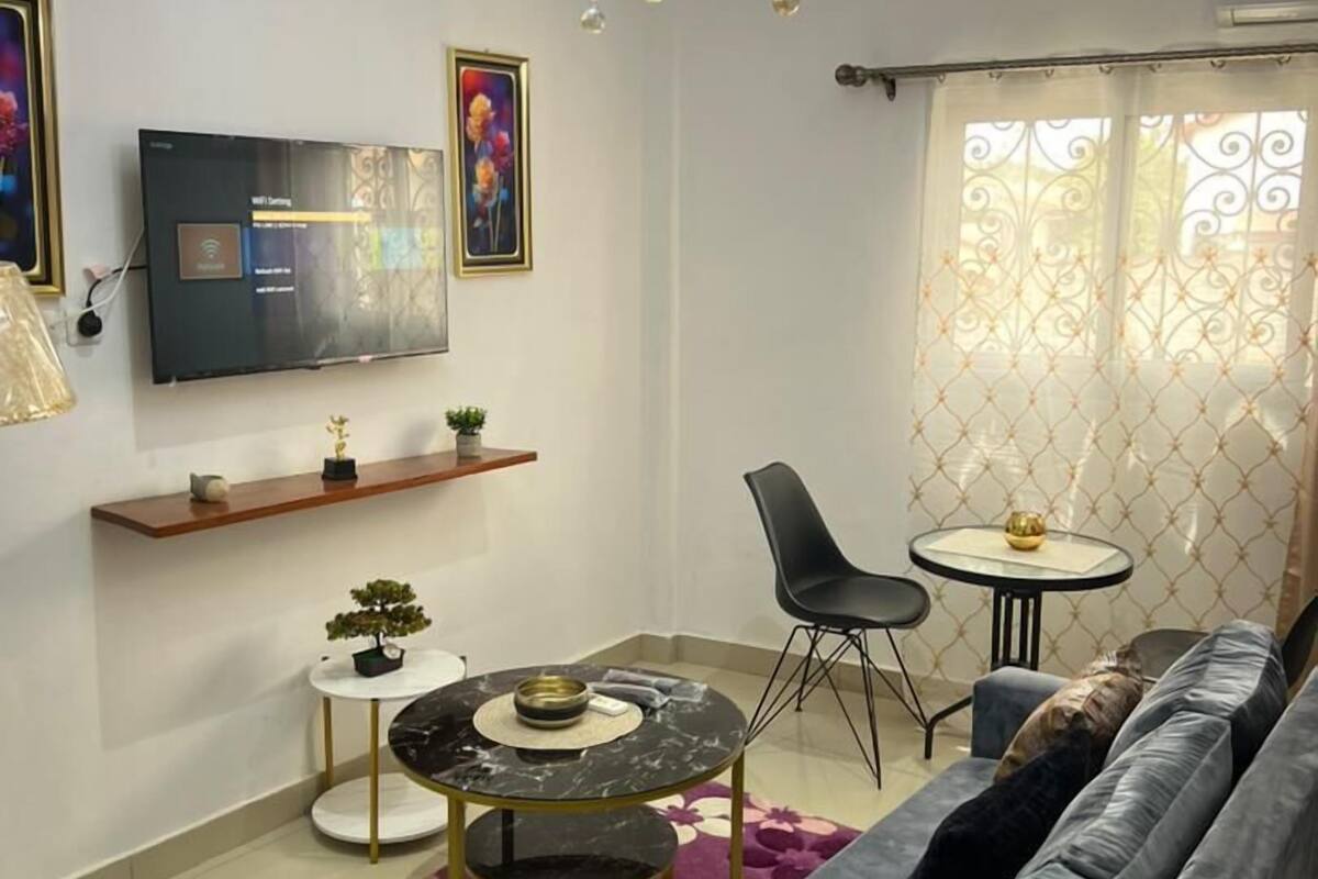 Una sala de estar moderna con un conjunto de sofás, una mesa de comedor y un televisor montado en la pared.