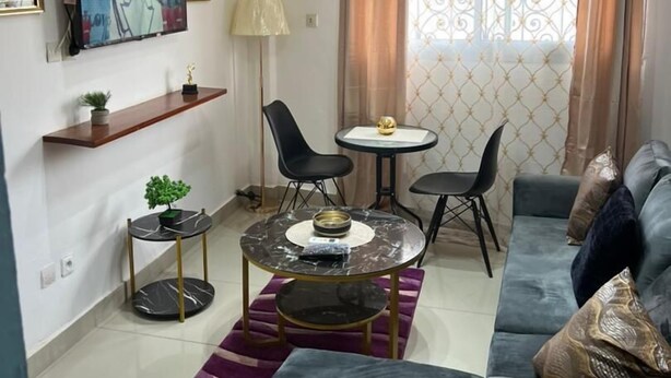 A modern living room with a sofa, a coffee table, and a TV mounted on the wall. - Lekker Estate (Yaoundé)