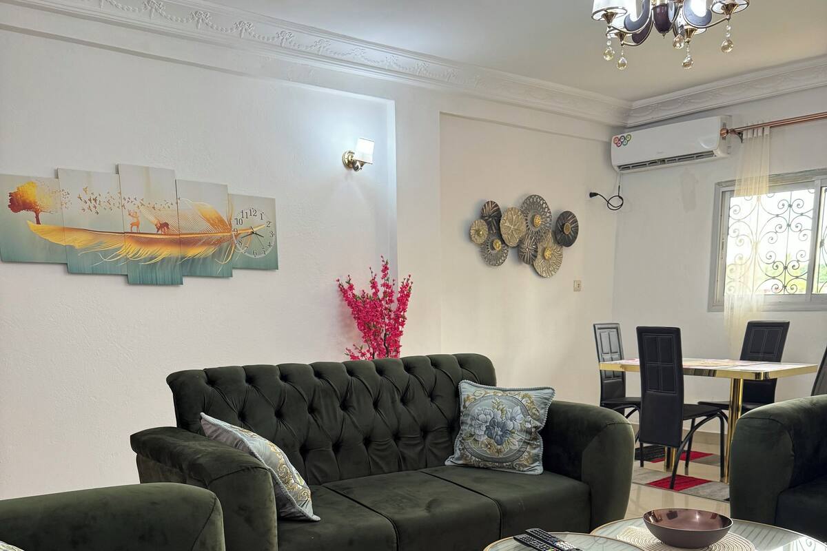 Una sala de estar con un sofá verde oscuro, una mesa de centro y una mesa de comedor con sillas.