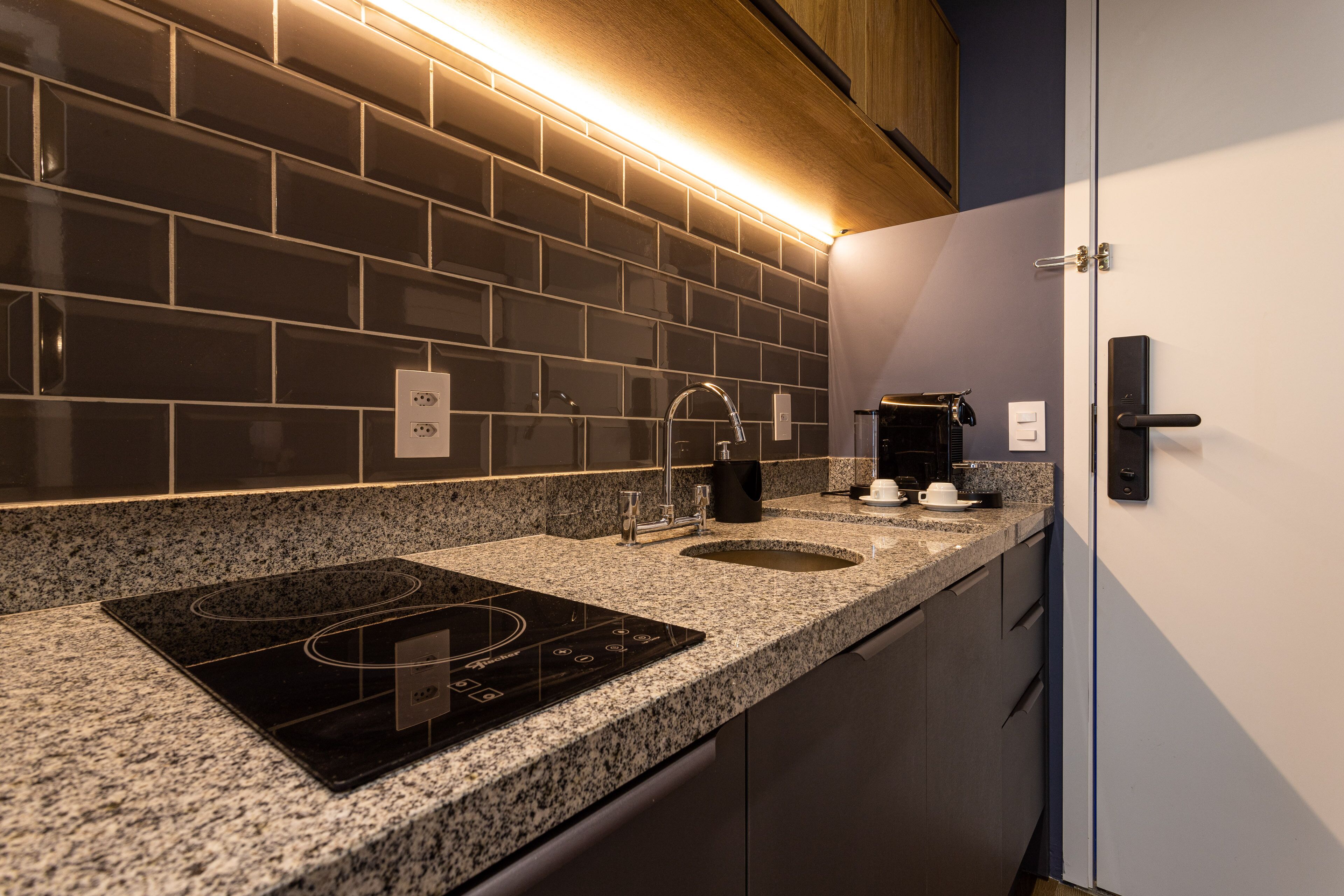 A modern kitchen with a black induction cooktop, double sink, and stainless steel faucet.