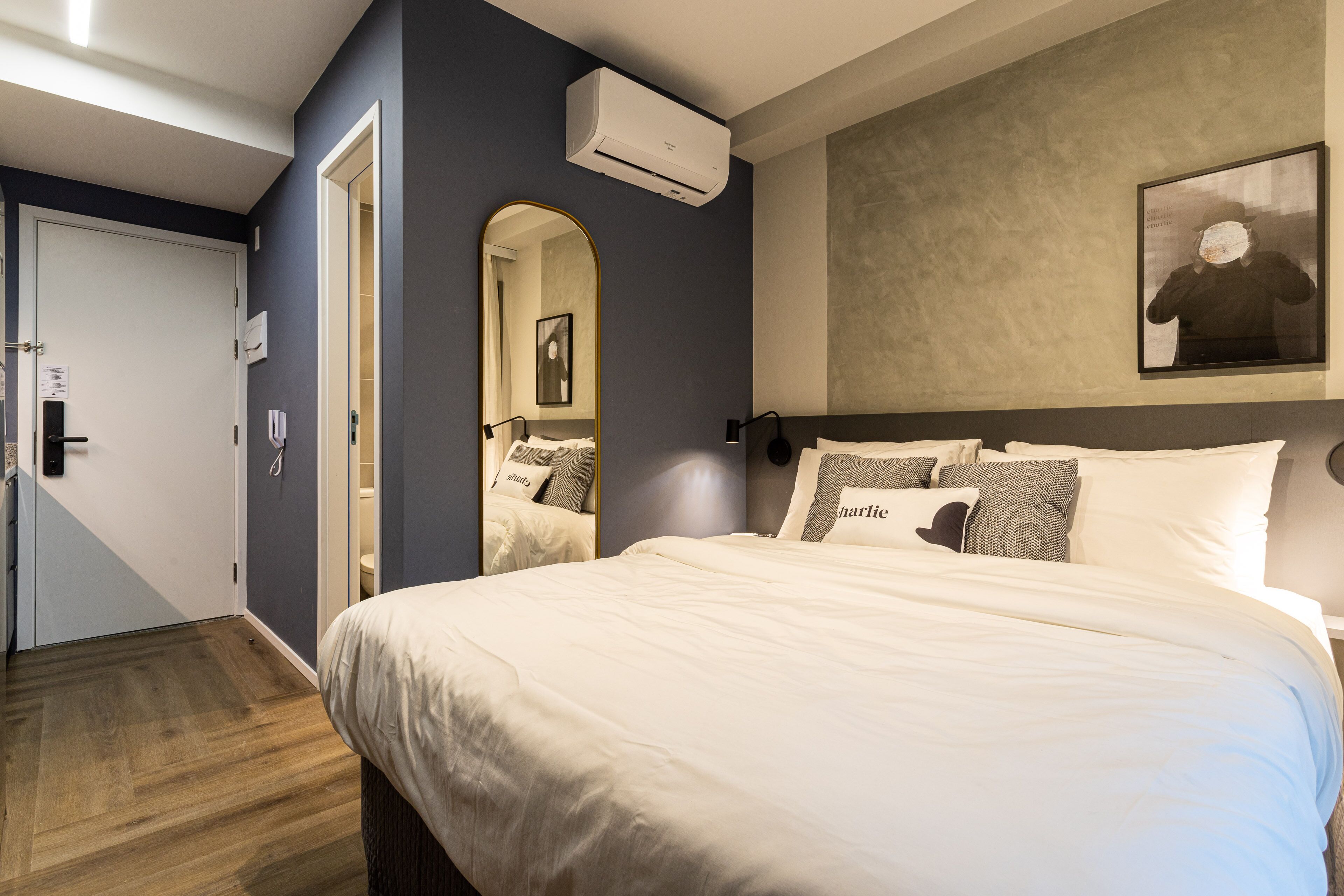 Una camera da letto con un letto grande, uno specchio, un condizionatore d'aria e un quadro appeso al muro.