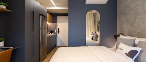 Un dormitorio moderno con una cama grande, un escritorio y una kitchenette.