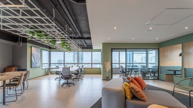 Un espacio de oficina moderno con una amplia mesa de reuniones, asientos cómodos y ventanas grandes que ofrecen vistas de la ciudad.