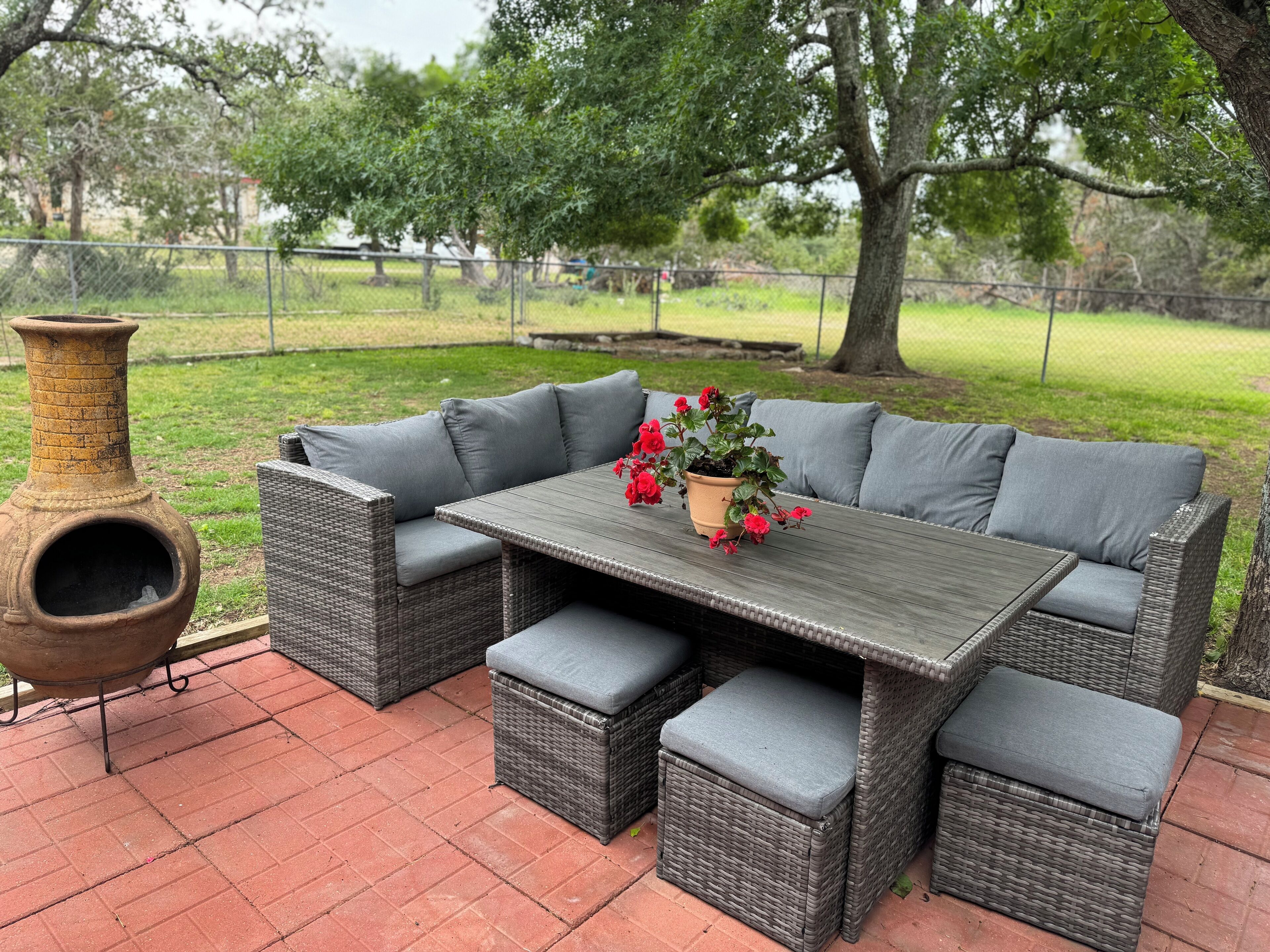 Une terrasse extérieure aménagée avec des meubles en osier, une table et un grand vase.