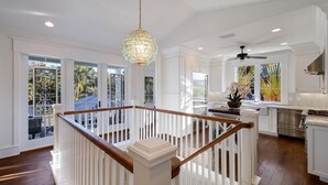 Una cocina amplia con armarios blancos, estufa de acero inoxidable y un ventanal con vistas a un jardín.